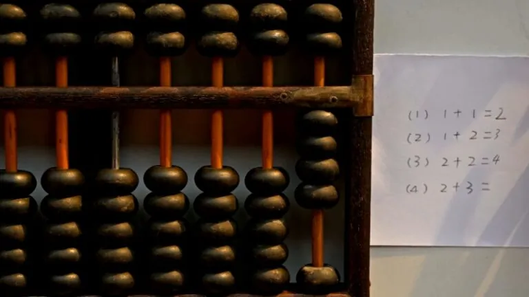 Abacus with a paper listing simple addition problems, demonstrating a visual method to teach addition to young children