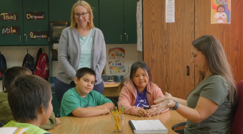 A teacher and a mentor engages with students in a classroom setting