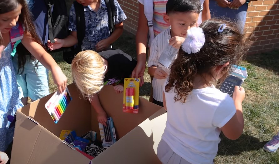 Children eagerly select school supplies from a large donation box