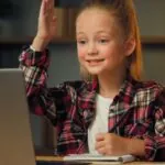 A young girl sits at a desk, engaged in a digital learning experience