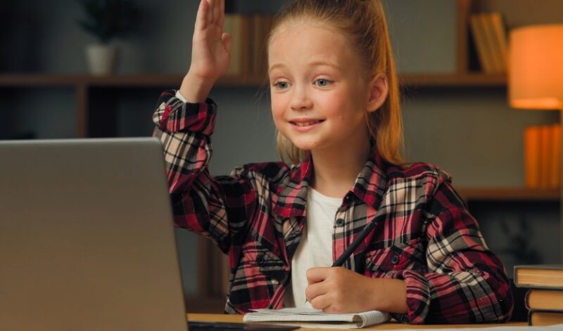 A young girl sits at a desk, engaged in a digital learning experience