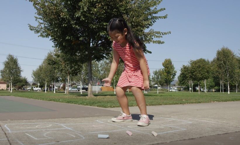 A kid is playing hopscotch on the playground