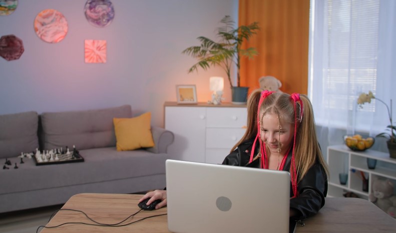 A young student interacts with a laptop, completing an educational activity