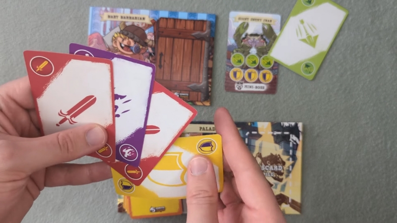 A player holds colorful action cards during a fast-paced round of 5-Minute Dungeon