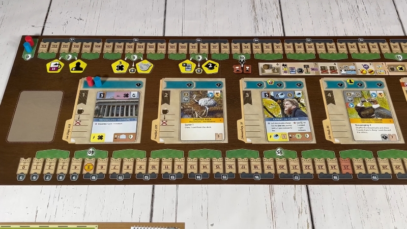 Ark Nova board game in play showing animal cards, tokens, and a central track with various action icons and player markers