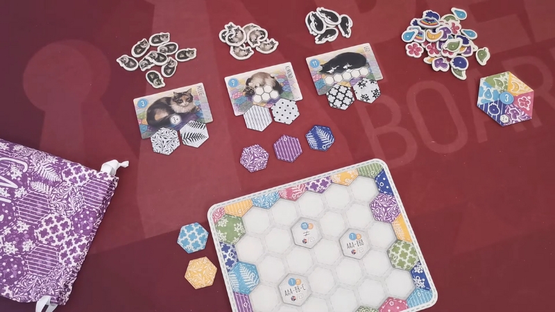 A game of Calico set up with cat tiles, colorful patch tokens, and a quilt board ready for strategic tile placement