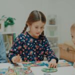 Three children engrossed in a board game, focused on the colorful pieces and spinning wheel