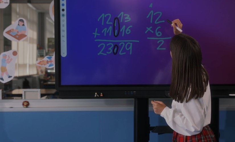 A student diligently solves a math problem on an interactive whiteboard