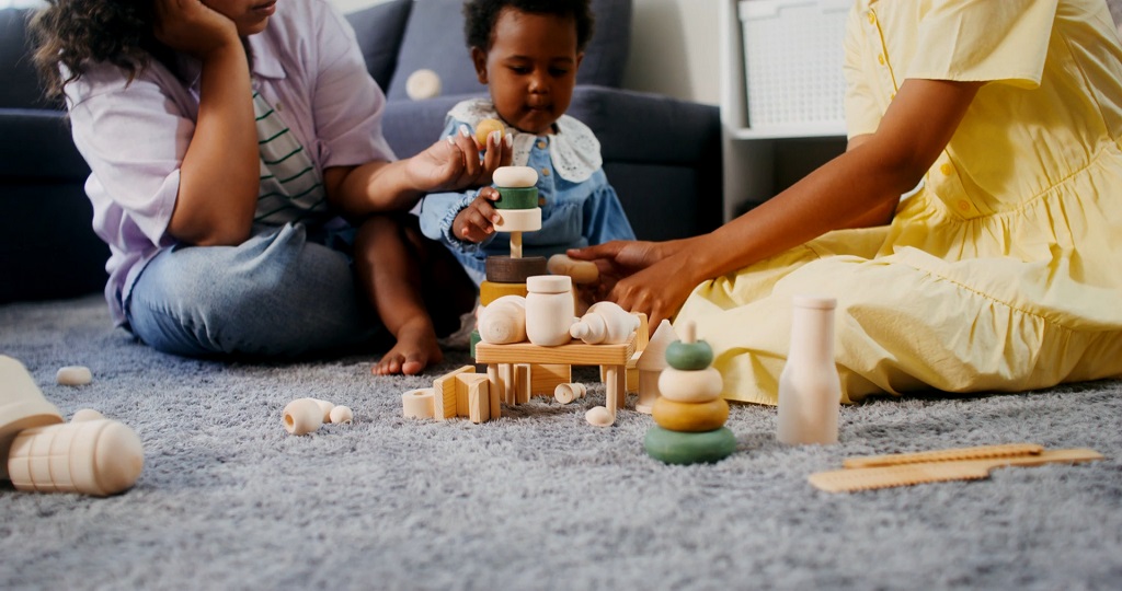 Parent observing child play with blocks on the floor