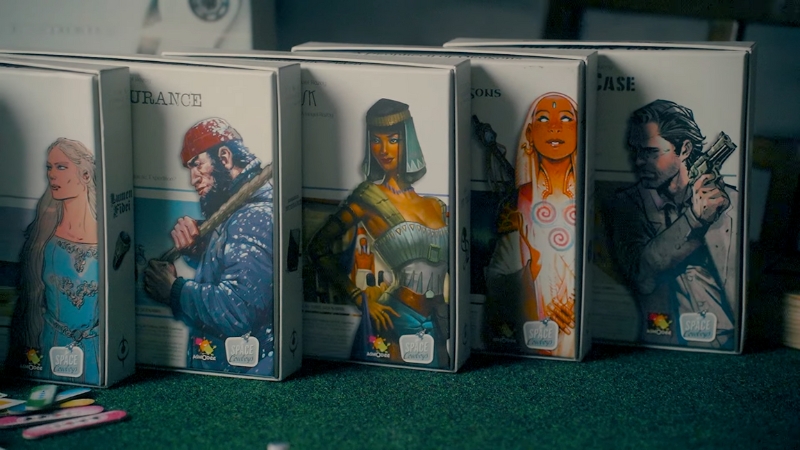 Boxes of T.I.M.E Stories expansions are lined up on a green table