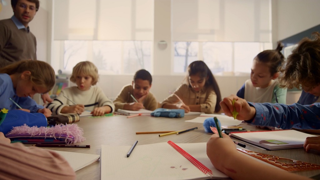 Group of preschool and kindergarten kids drawing and writing with math books by grade as part of playful learning