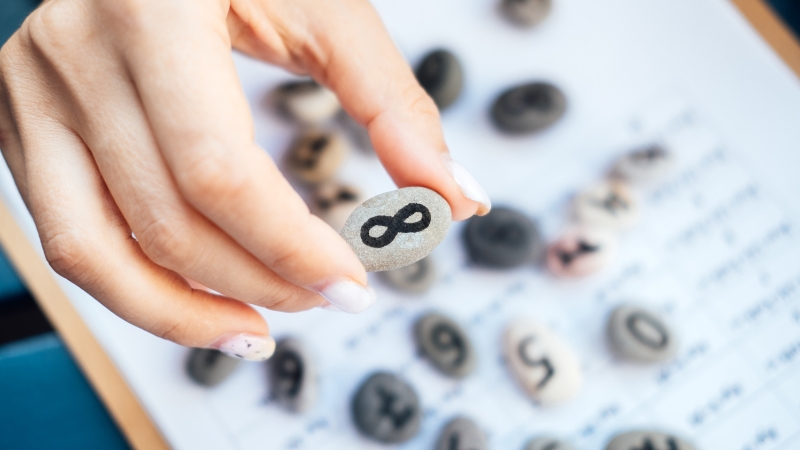 A hand holding a stone with the infinity symbol, used as a learning tool to explain infinity in math