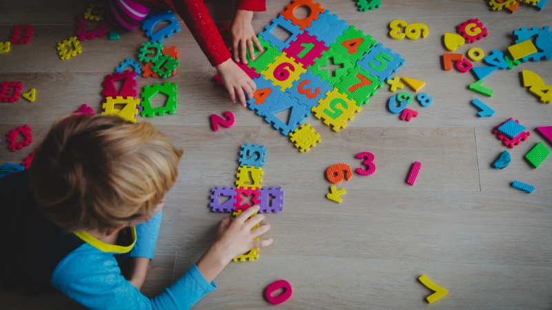 Children solving colorful number puzzles on the floor, illustrating Infinity in Math quick puzzles for kids
