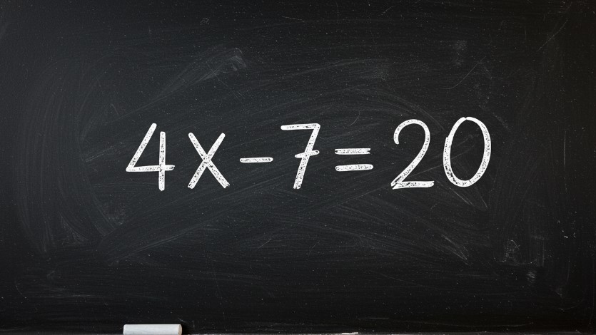 The equation 4x - 7 = 20 is written in white chalk on a black chalkboard