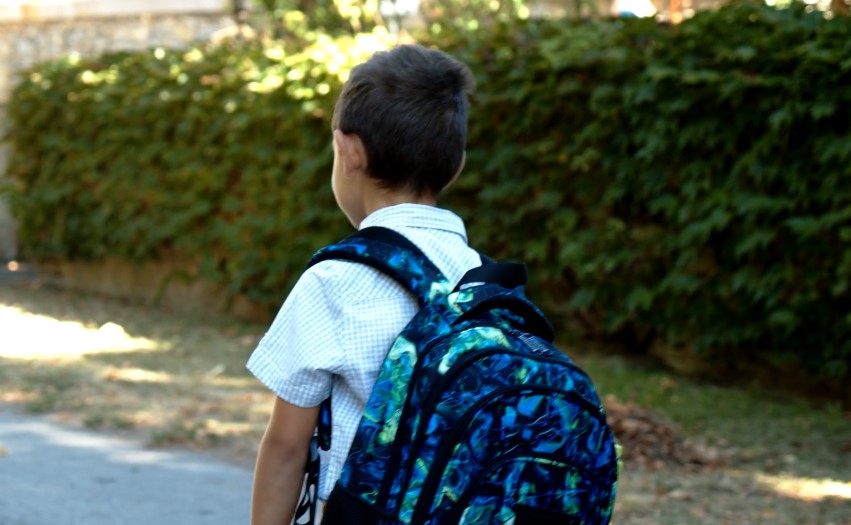 A young boy with a backpack walking down a street