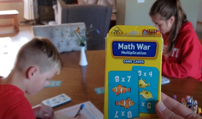 Brother and sister playing math card game at the table