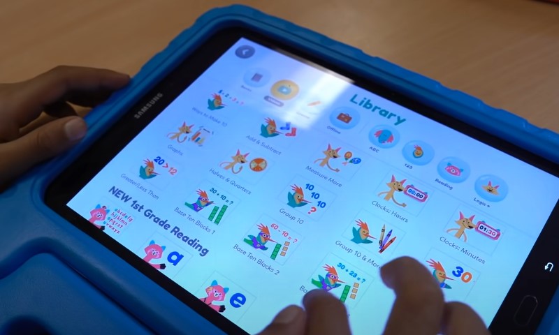 A child interacts with a tablet displaying various colorful icons on the screen