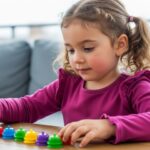 A little girl joyfully playing with a variety of colorful toys scattered around her