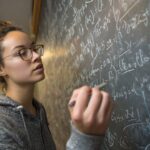 Student writing complex integral equations on a chalkboard