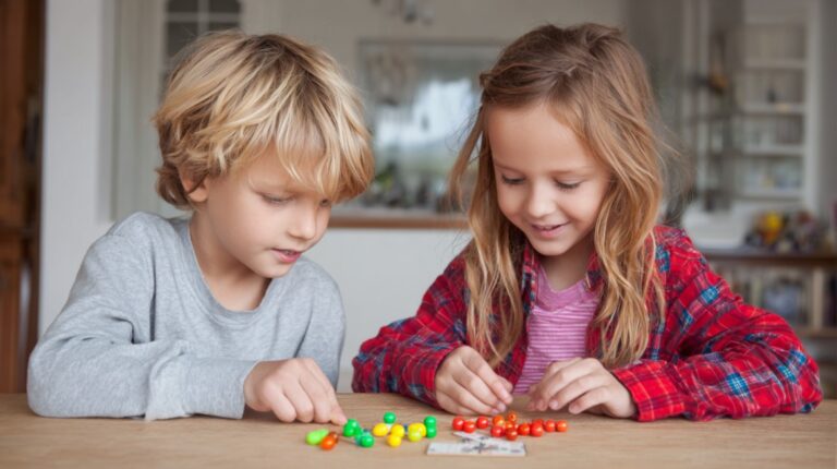 Two young children sorting colorful pieces at a table indoors