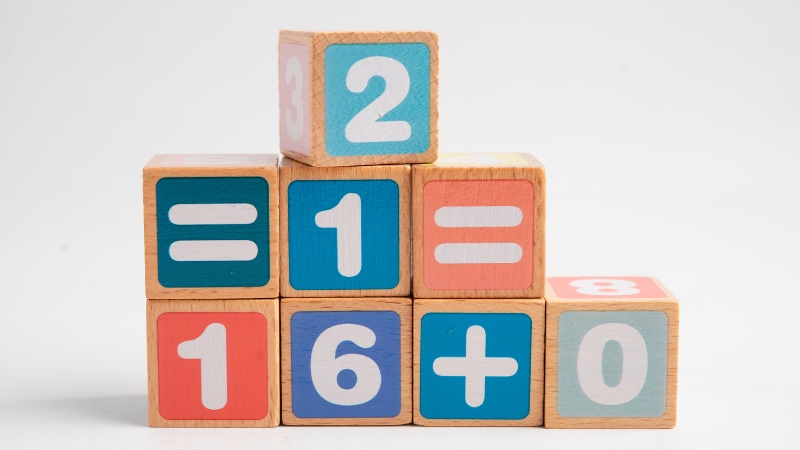 Wooden math blocks show numbers and symbols that represent basic arithmetic in school math